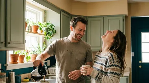 A couple laughing in a sunny kitchen