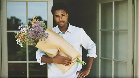 A man arriving home with groceries and flowers