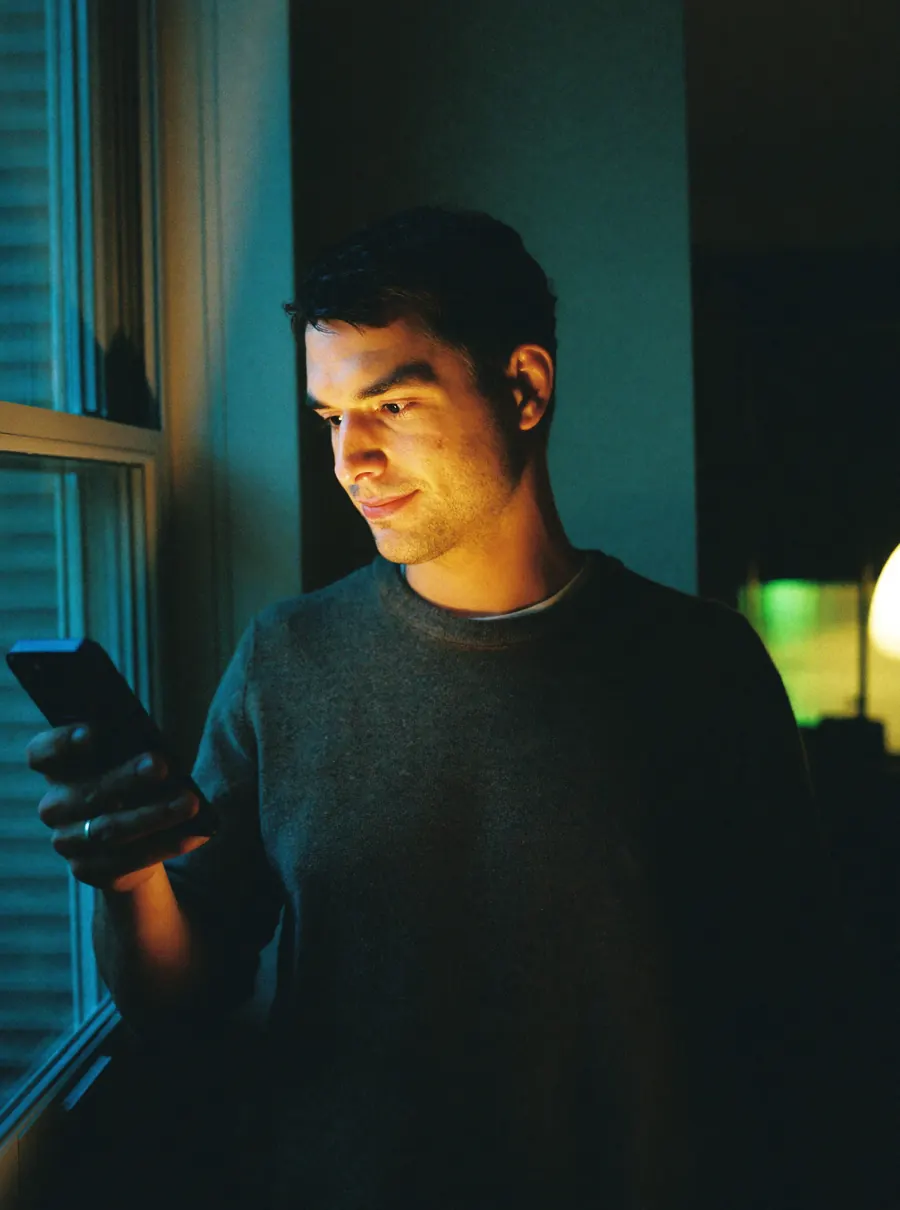 A man at home in the evening, checking Cue on his phone